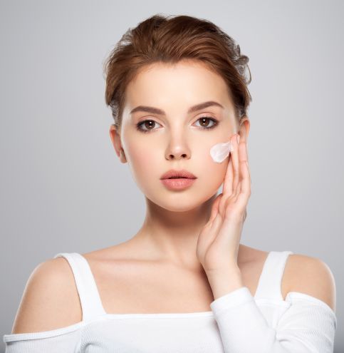 Spot of cosmetic cream on a woman's face. Beautiful face of young caucasian woman with perfect healthy skin, isolated.   Pretty white model caring of face.  Woman applying cream on face.